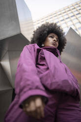 Junge afroamerikanische Frau in warmer Kleidung, die gegen ein gebautes Gebäude blickt - IFRF00267