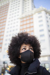 Junge Afro-Frau, die während der Pandemie in der Stadt wegschaut - IFRF00279