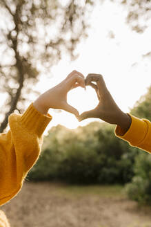 Couple making heart shape with hands at forest - EGAF01372