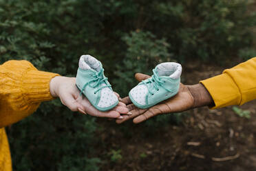 Close-up of couple holding baby booties at forest - EGAF01383
