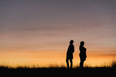 In silhouette of man and woman standing against sky - EGAF01413
