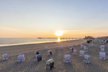 Germany, Mecklenburg-Western Pomerania, Ahlbeck, Hooded beach chairs on sandy coastal beach at sunrise - WDF06453