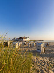 Germany, Mecklenburg-Western Pomerania, Ahlbeck, Hooded beach chairs on sandy coastal beach with bathhouse in background - WDF06454