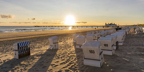 Germany, Mecklenburg-Western Pomerania, Ahlbeck, Hooded beach chairs on sandy coastal beach at sunrise - WDF06463