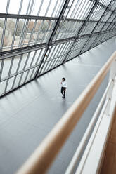 Young male professional walking by roof in office corridor - JOSEF02852