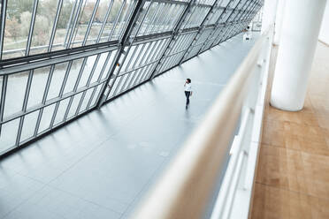 Young male entrepreneur walking by roof in office corridor - JOSEF02909