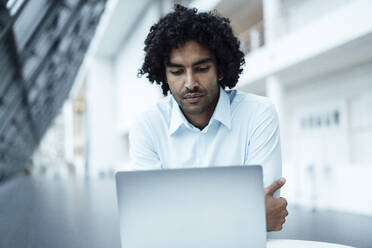 Confident young male entrepreneur using laptop at office - JOSEF02912