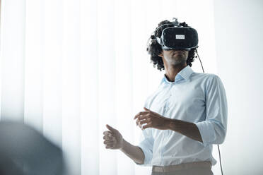 Young male entrepreneur wearing virtual reality headset in board room at office - JOSEF02948