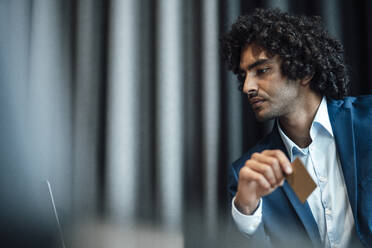 Confident male entrepreneur holding credit card at office - JOSEF03023