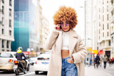 Stylish woman with blond hair wearing sunglasses standing on street - OCMF01959