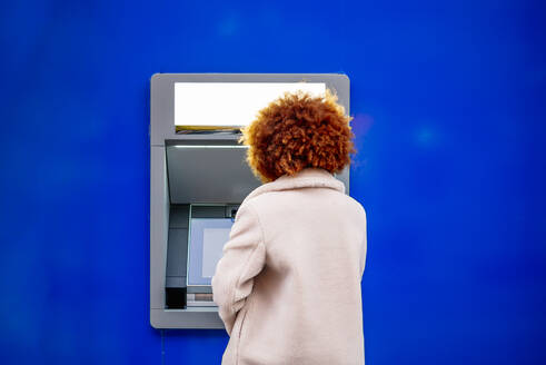 Mid adult woman with afro hair using kiosk in city - OCMF01964