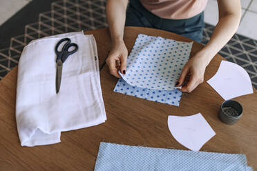 Woman holding fabric to carves mask at home - OGF00731