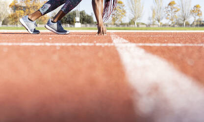 Sportswoman at start line on running track during sunny day - JCCMF00527