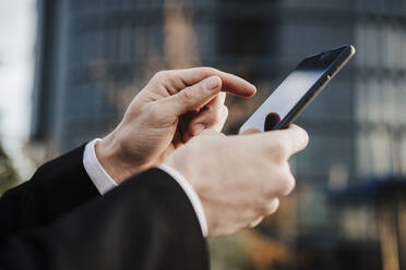 Close-up of businessman using smart phone outdoors - EBBF02022