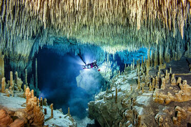 Männlicher Höhlentaucher bei der Erkundung von Stalaktiten und Stalagmiten im Meer, Cenote Uku Cusam, Quintana Roo, Mexiko - YRF00236