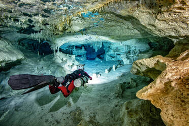 Männlicher Höhlentaucher bei der Erkundung zwischen Felsen im Meer, Cenote Dos Pisos, Quintana Roo, Mexiko - YRF00242