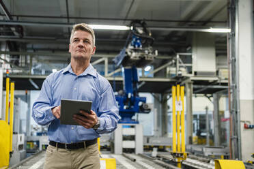 Mature supervisor holding digital tablet while looking away in industry - DIGF13997
