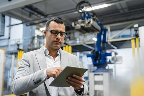 Älterer Geschäftsmann mit Brille, der in der Industrie an einem digitalen Tablet arbeitet - DIGF14006