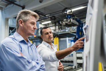 Ein männlicher Unternehmer erklärt seinem Vorgesetzten während einer Besprechung in einer Fabrik die Geschäftsstrategie - DIGF14014