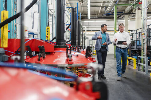 Geschäftsleute diskutieren beim Gehen in einer Fabrik - DIGF14021