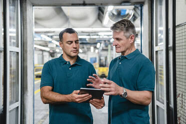 Männlicher Ingenieur im Gespräch mit einem Kollegen in einer Fabrik - DIGF14043