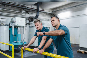 Male technician gesturing while discussing with coworker in factory - DIGF14050