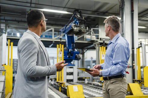 Männliche Fachkräfte mit digitalem Tablet, die sich die Maschinenausstattung in einer Fabrik ansehen - DIGF14085