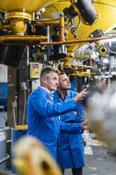 Männliche Techniker bei der Arbeit in der Fabrik im Gespräch über die Herstellung - DIGF14140