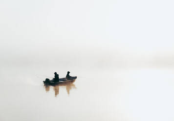 Mann und Kind beim Angeln in einem Boot bei dichtem Nebel auf einem See. - CAVF91463