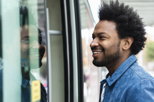 Nahaufnahme eines stilvollen erwachsenen Mannes mit Afro-Haar, der in einen Bus einsteigt - PNAF00471