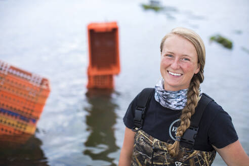 Porträt einer Muschelzüchterin im Wasser stehend - CAVF91484