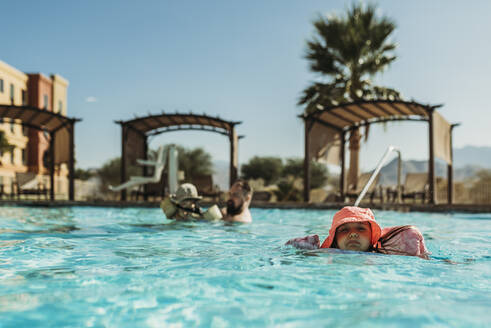Junges Mädchen im Vorschulalter schwimmt im Pool im Urlaub in Palm Springs - CAVF91500