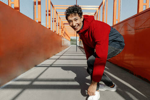 Cheerful young man standing on footbridge - OGF00762