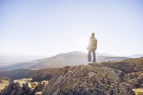 Female hiker standing on top of mountain against clear sky during sunny day - RSGF00484