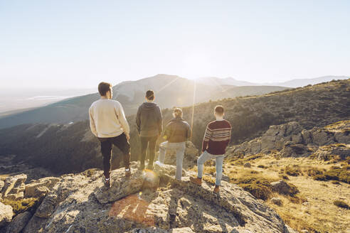 Friends looking at view while standing on mountain during sunny day - RSGF00493