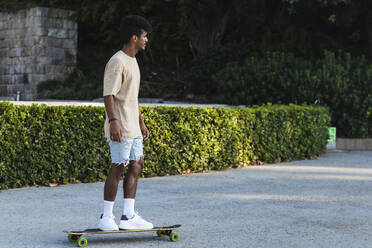 Junger Mann fährt Skateboard auf der Straße im Park - PNAF00511