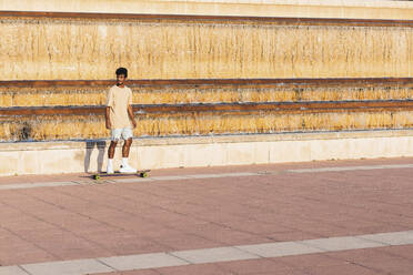 Young man skateboarding on footpath at sunset - PNAF00515