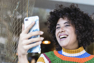 Young woman smiling while using mobile phone at restaurant - PNAF00548