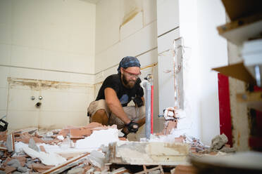 Ein Mann arbeitet an einem Heimwerkerprojekt, umgeben von Trümmern einer Mauer - CAVF91523