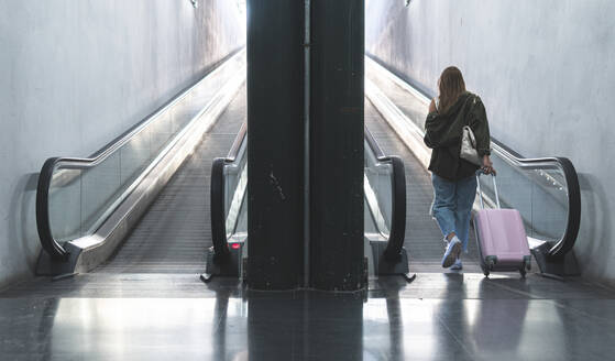 Junge Frau mit Koffer geht auf einen Fahrsteig am Bahnhof zu - JAQF00133