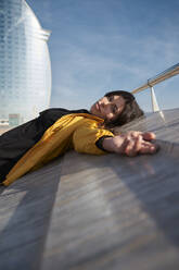 Schöne Frau auf einer Stützmauer liegend an einem sonnigen Tag - VEGF03532