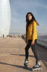 Young woman with roller skate on pier against sky - VEGF03533