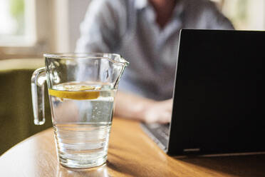 Männlicher Unternehmer arbeitet über einem Laptop auf einem Tisch zu Hause - MEF00095