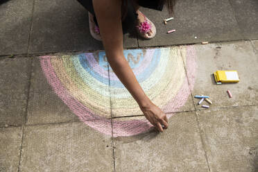 Arm of adult woman drawing crayon rainbow on pavement - PMF01699