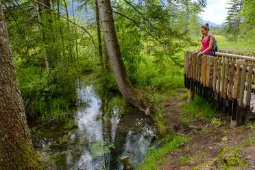 Wanderin bewundert die durch das Naturschutzgebiet Ettaler Weidmoos fließende Ammer im Frühling - LBF03289