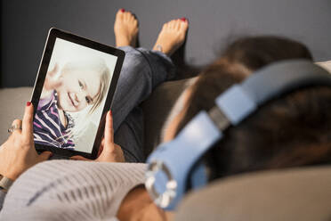 Mother making video call to daughter through digital tablet at home - UUF22395