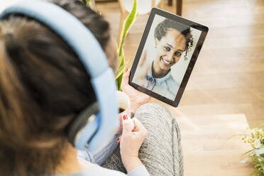 Multiethnische Freundinnen bei einem Videoanruf über ein digitales Tablet zu Hause - UUF22408