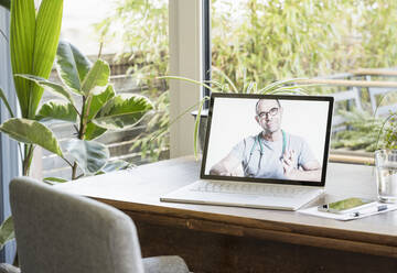 Männlicher Arzt gibt Ratschläge per Videoanruf auf dem Laptop zu Hause - UUF22424