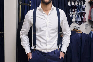 Customer in white shirt and blue suspenders in tailors boutique - AODF00185