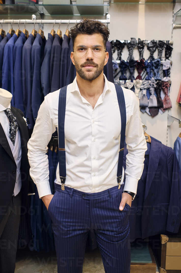 Portrait of customer in white shirt and blue suspenders in tailors boutique  stock photo